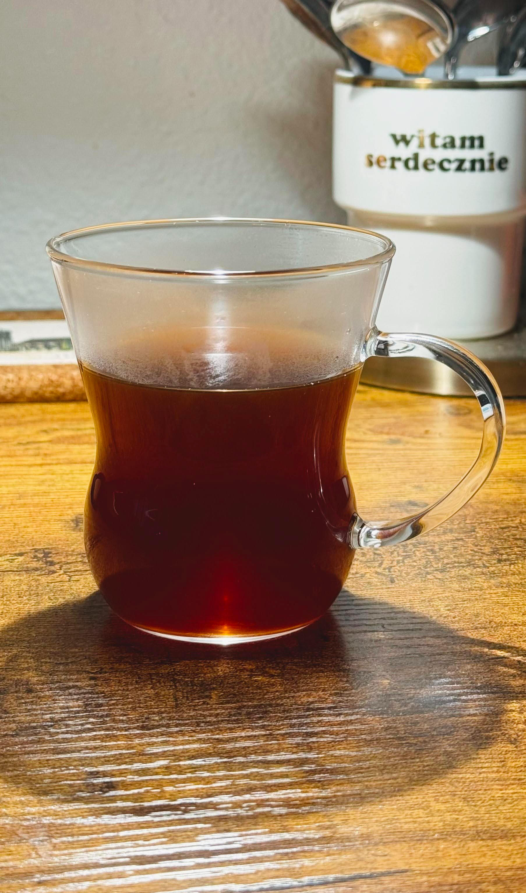 A steaming cup of Telos Coffee in a glass mug